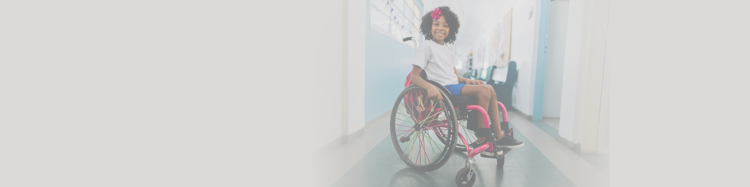 Black girl with curly afro with wheelchair disability smiling at camera