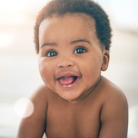 Black baby with low afro smiling at camera