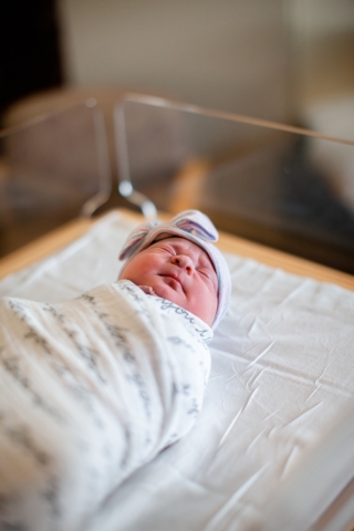 newborn baby wrapped in hospital blanket wearing hat