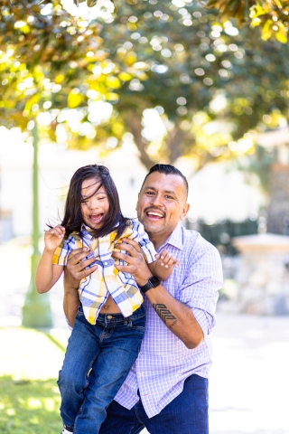 Latinx father lifting up daughter with developmental disability