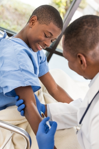 Black Boy in hospital gown getting vaccine from Black male physician