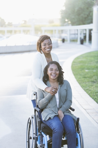 Black mother with daughter in wheelchair hugging