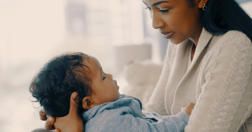 Cropped shot of an adorable little baby boy sleeping in his mothers arms at home